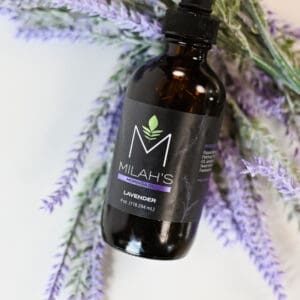 A bottle of plant oil sitting on top of a bunch of lavender.