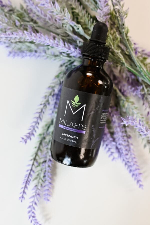 A bottle of plant oil sitting on top of a bunch of lavender.