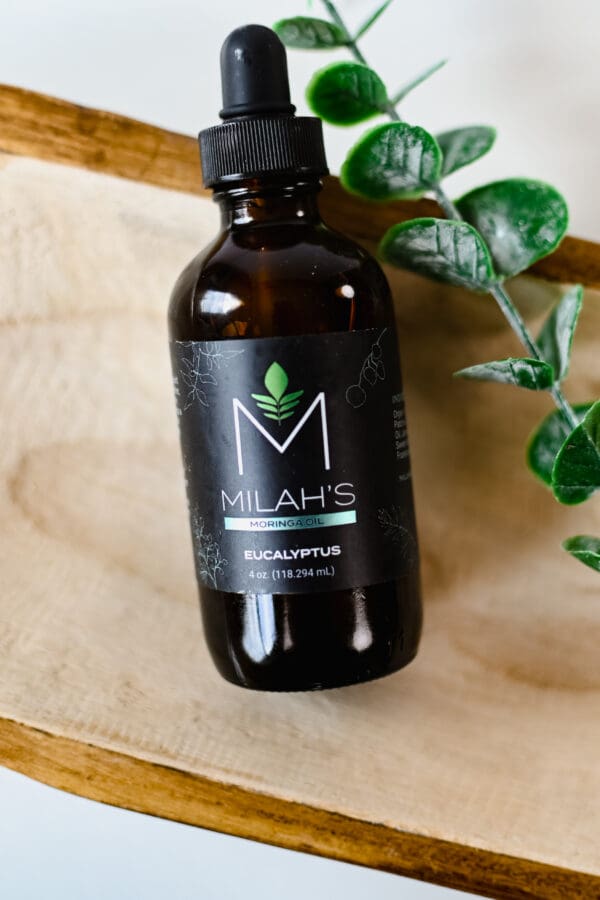 A bottle of milah 's cbd oil sitting on top of a wooden board.